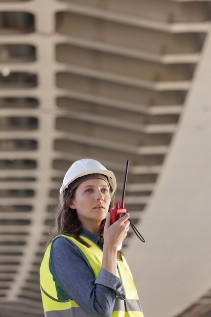 Female engineer with a walkietalkie at the construction site gives instructions European successful female technologist