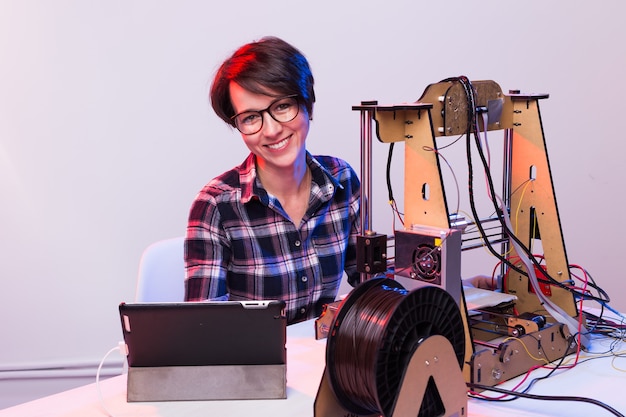 Female engineer working at night in the lab, he is adjusting a printer components