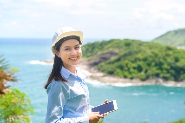 保護用ヘルメットをかぶって海辺で働く女性エンジニアx9