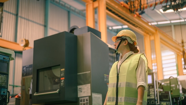 女性エンジニアが工場の機械を検査します。植物工場、労働産業の仕事の概念