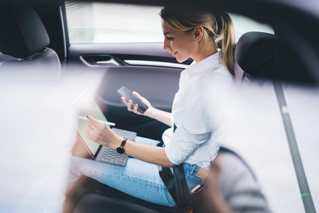 female entrepreneur enjoying online communication via modern digital devices while sitting in car