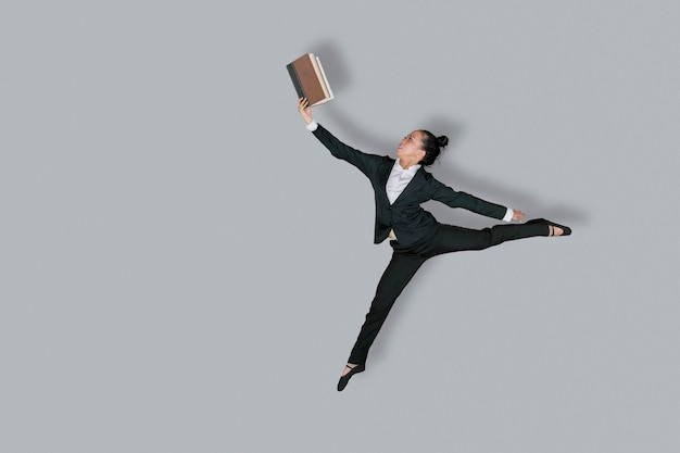 Photo female entrepreneur jumps with book on studio