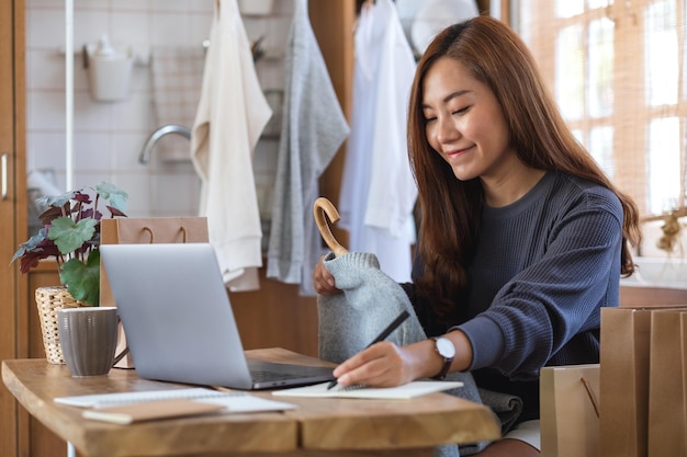 服を販売し、オンラインショッピングの概念のために顧客からの注文をチェックする女性起業家