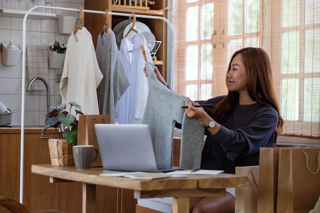 A female entrepreneur using laptop computer for selling clothes online or review product on social media at home