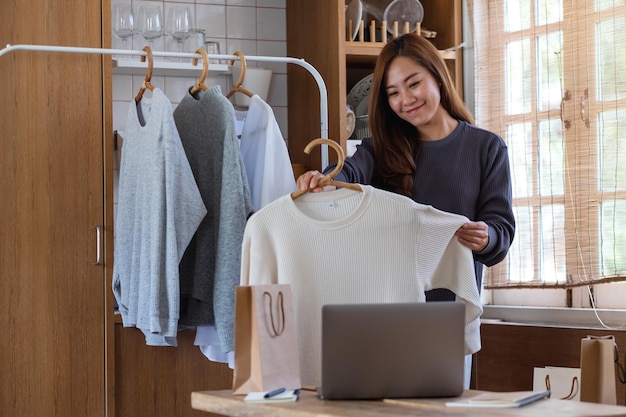 A female entrepreneur using laptop computer for selling clothes
online or review product on social media at home