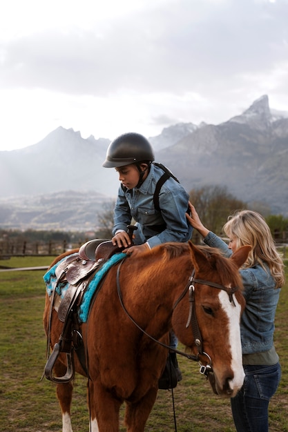 Foto istruttore equestre femminile che insegna al bambino come andare a cavallo