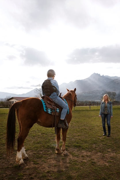 写真 子供に馬の乗り方を教える女性馬術インストラクター