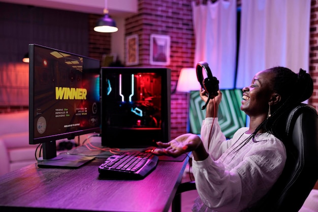 Female esport gamer streaming online video games play on pc, playing action game championship in place with neon lights. Female player having fun with gaming tournament on stream.