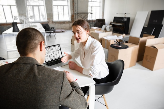 Female estate agent showing new home to a young man after a discussion on house plans moving new home concept