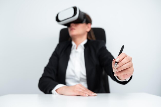 Female Executive Holding Pen And Learning Professional Skill Through Virtual Reality Simulator Woman Wearing Suit Sitting At Desk And Presenting Modern Training Techniques