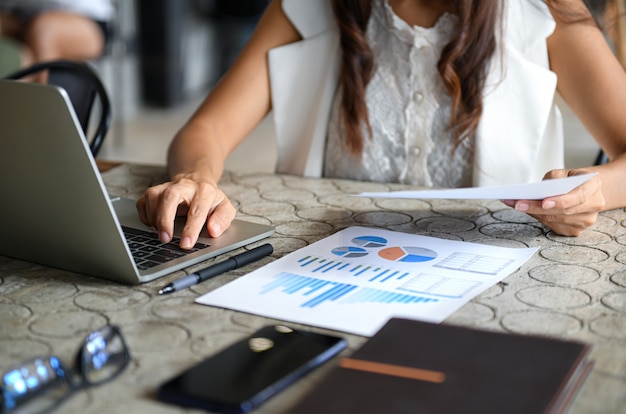 Female executive use laptop and check the data graph of the company.