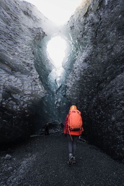 Foto esploratrice femminile che cammina verso la grotta di ghiaccio, islanda