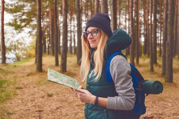 Женский исследователь с картой на открытом воздухе в лесу осенью