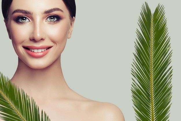 여성의 얼굴과 녹색 잎 건강한 피부와 귀여운 미소를 지닌 스파 여성 모델 페이셜 트리트먼트 미용 및 스파 뷰티