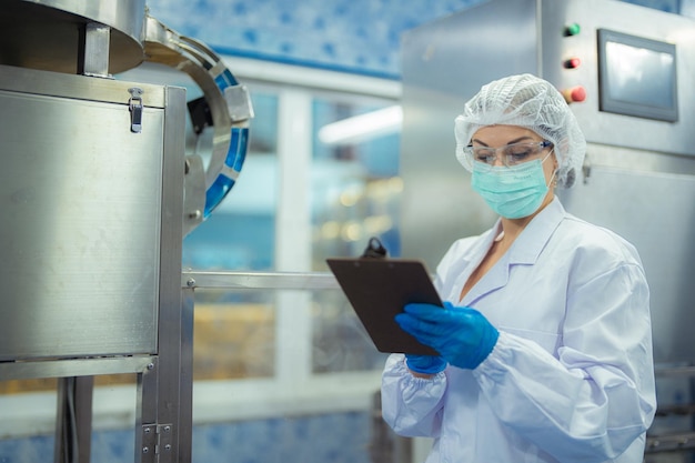 Female factory worker checks machine systems at the industrial factory