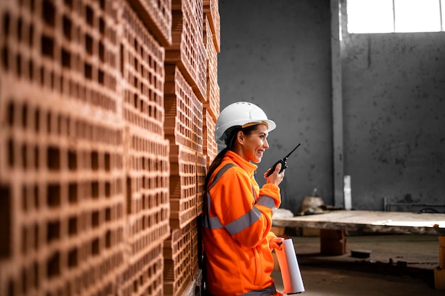 Female factory worker using radio for communication during loud manufacturing process