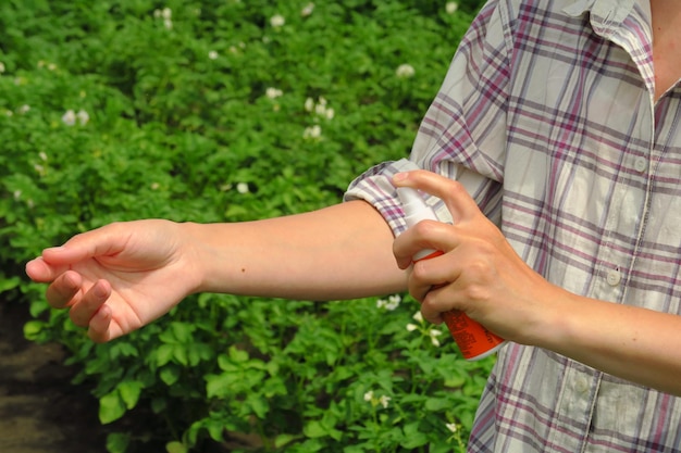 a female farmer applies mosquito and tick spray to her skin to protect herself from infections