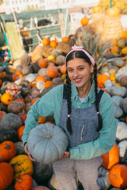 Female farmer holding pumpkin on the background of autumn harvest