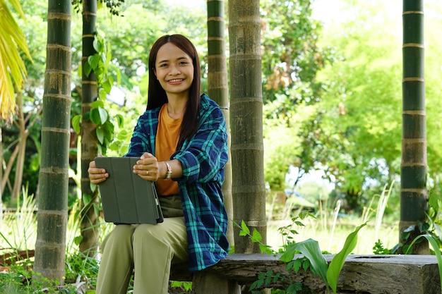 Female farmer is happy after viewing results from a laptop computer banana plantation background