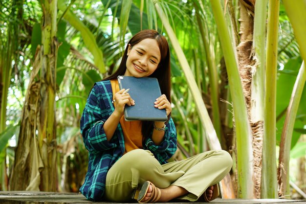 Female farmer is happy after viewing results from a laptop computer Increased profits Banana plantation background