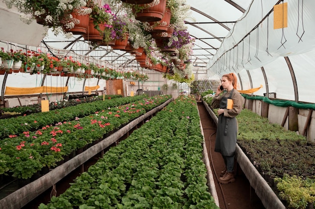 Contadina che lavora in una grande serra industriale e vivaio di fiori