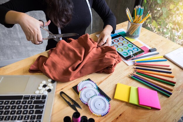 Foto designer di moda donna che taglia tessuto al banco di lavoro