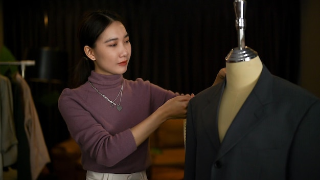 Foto una stilista femminile che misura il suo modello di abito su un manichino con nastro adesivo di misurazione