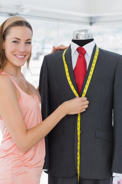 Female fashion designer measuring suit on dummy