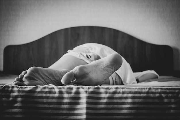 Female feet on bed, close-up of young woman's feet