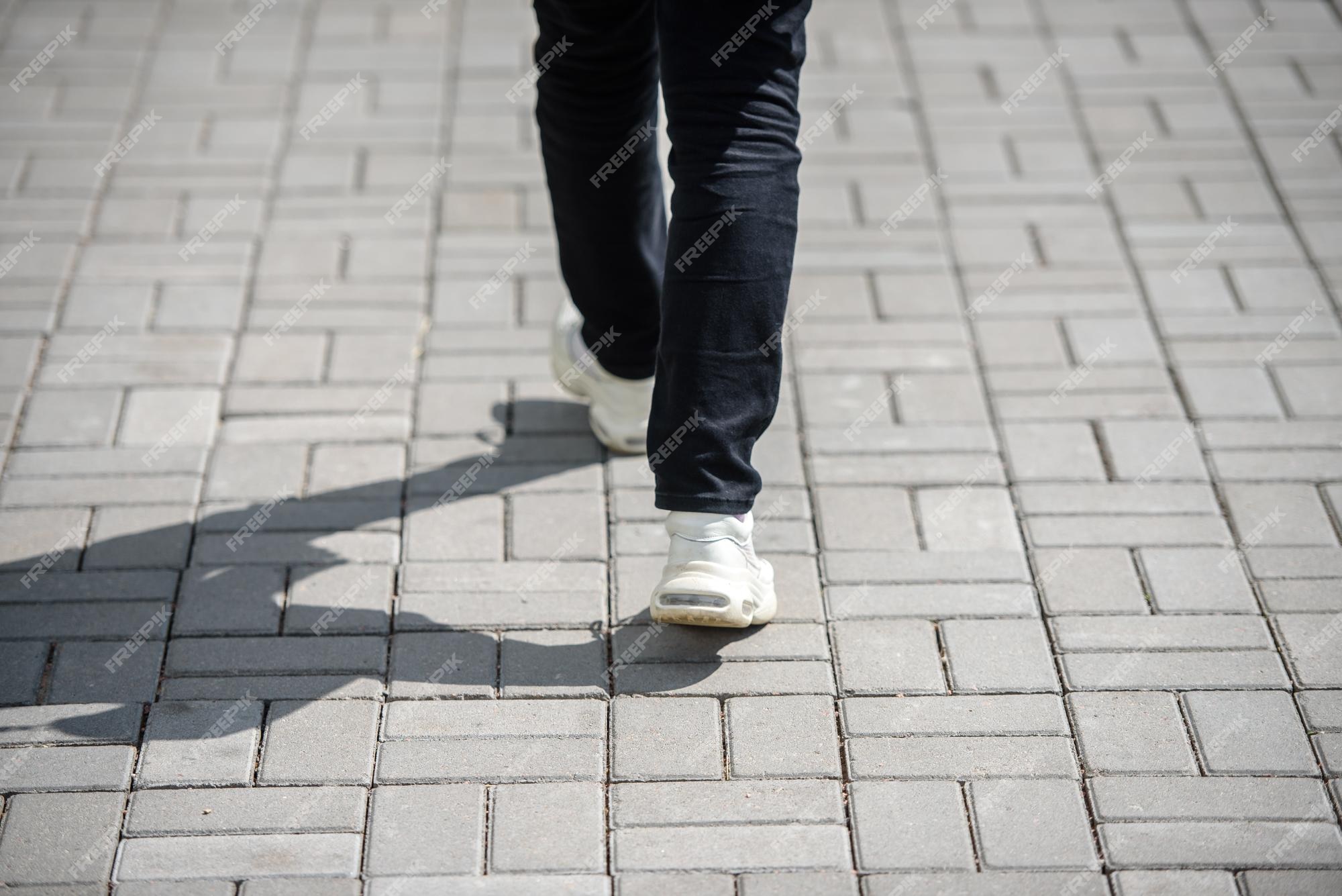 carbón Viaje Proceso Premium Photo | Female feet in black jeans and white sneakers walking on  the sidewalk in the city