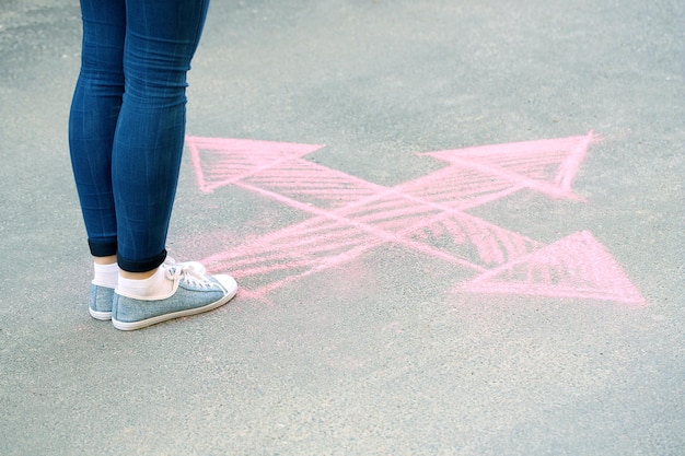 Female feet and drawing arrows on pavement background