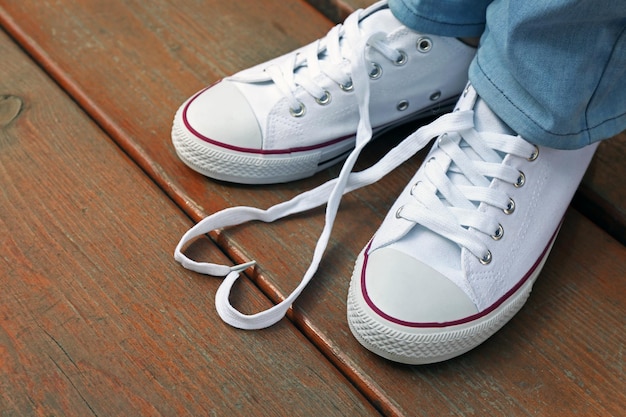 Female feet in gum shoes on wooden floor background