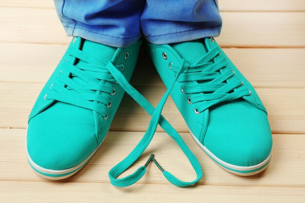 Female feet in gum shoes on wooden floor background