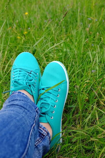 Female feet in gumshoes on green grass background