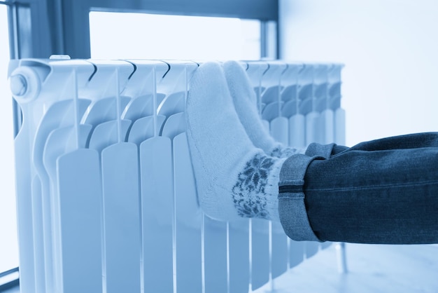 Female feet on heater wearing woolen socks