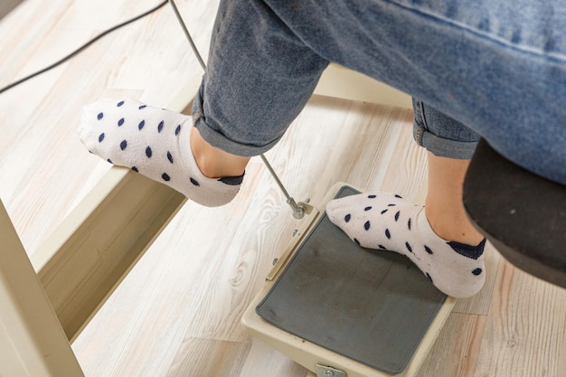 Female feet on the pedal of a sewing machine motor