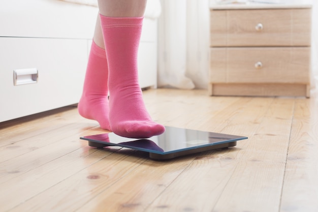 Female feet in socks on the floor scales