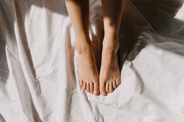 Female feet on white bed sheet