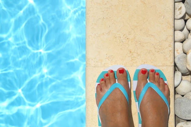 Female feet with flip flops by the pool