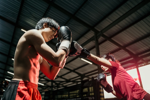 Female fighter attacking with punch motion while competing against male boxer at boxing camp