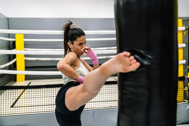 Female fighter training with a heavy bag in gym