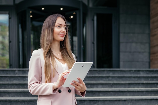 Analista finanziario femminile che tiene il tablet e distoglie lo sguardo