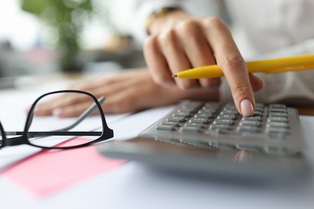 Female finger on a calculator near documents