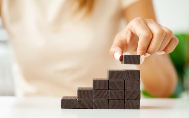 Female fingers climb ladder made of wooden blocks