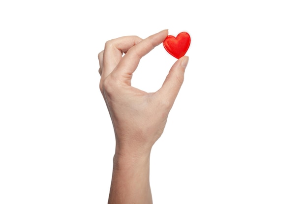 Female fingers hold a tiny red heart Symbol of love