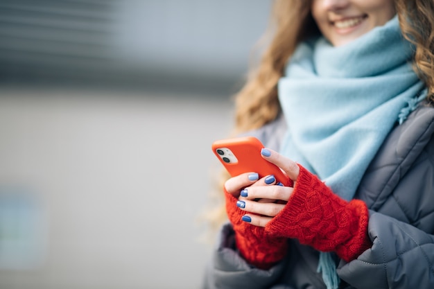 屋外で携帯電話をタップする女性の指。