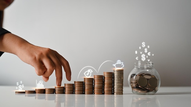 Фото Женские пальцы, поднимающиеся на стопку монет сбережение денег и концепция роста бизнеса