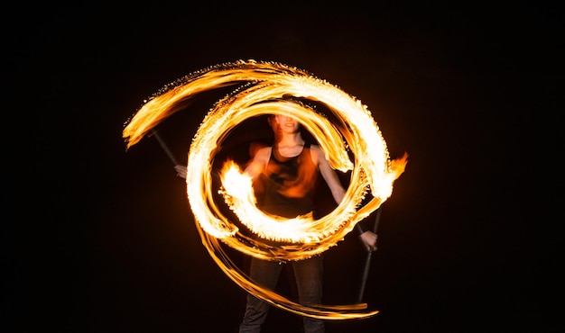 Photo female fire dancer twirl burning baton creating sparkling trails in motion dark outdoors twirler