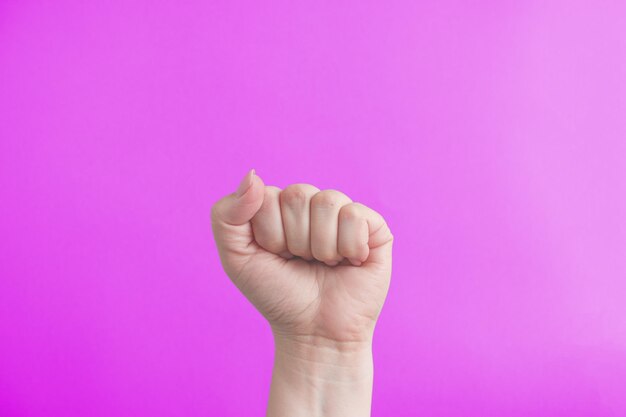 Female fist on a pink background The concept of feminism and the struggle for women's rights