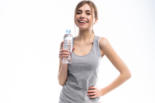 Female fitness model holding a water bottle in a white studio environment